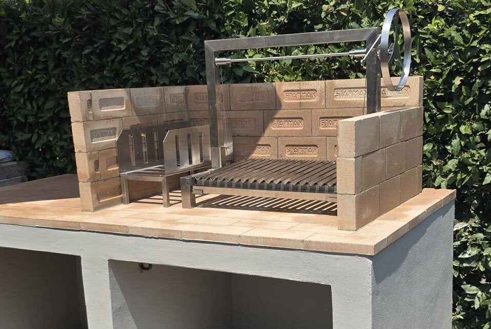 Standard Asado Grill aus Edelstahl mit integriertem Feuerkorb – montiert in einem Gartenkamin